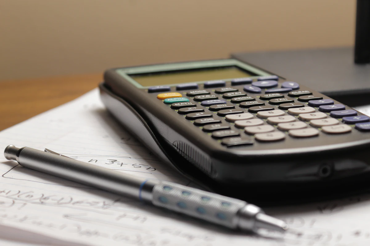A calculator and a pen on top of paper records