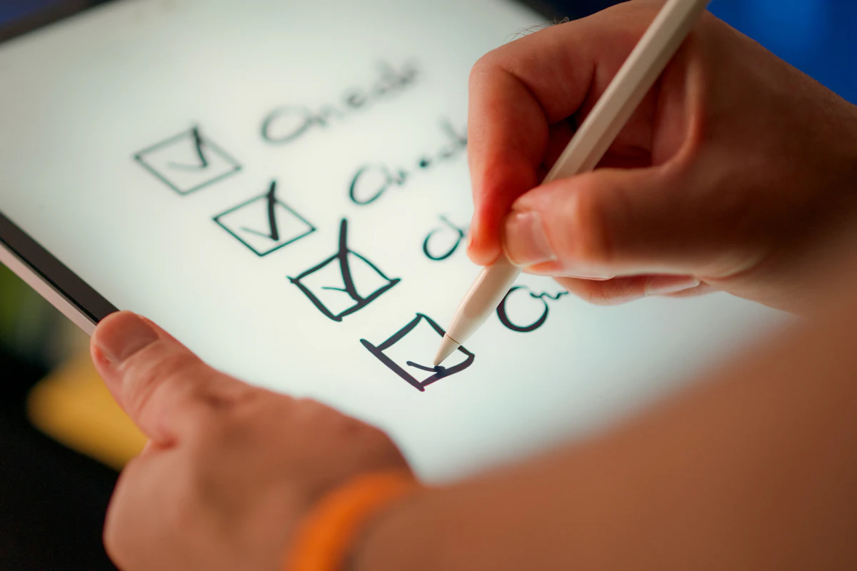A hand ticking boxes on a checklist on a tablet