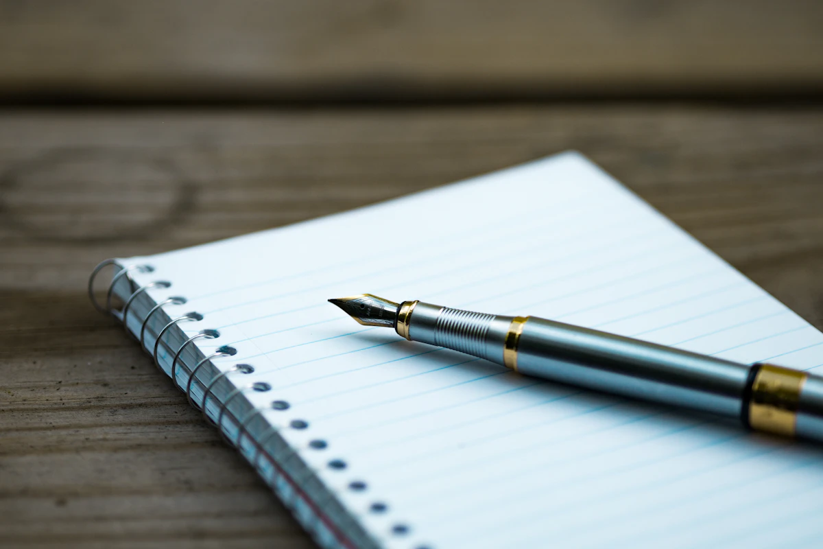 A fountain pen resting on a spiral notebook