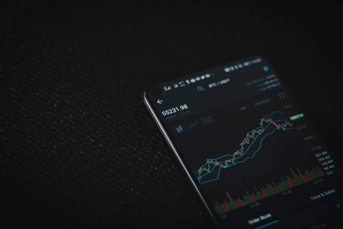 A phone on a dark surface showing a price chart